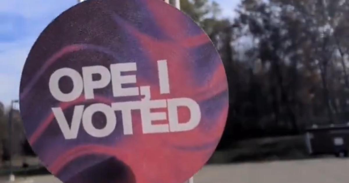 A screenshot of a woman holding an "Ope, I Voted" sticker