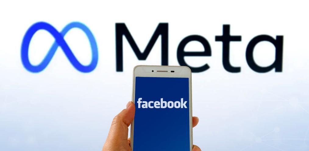 The Facebook logo on a phone held up in front of the Meta logo