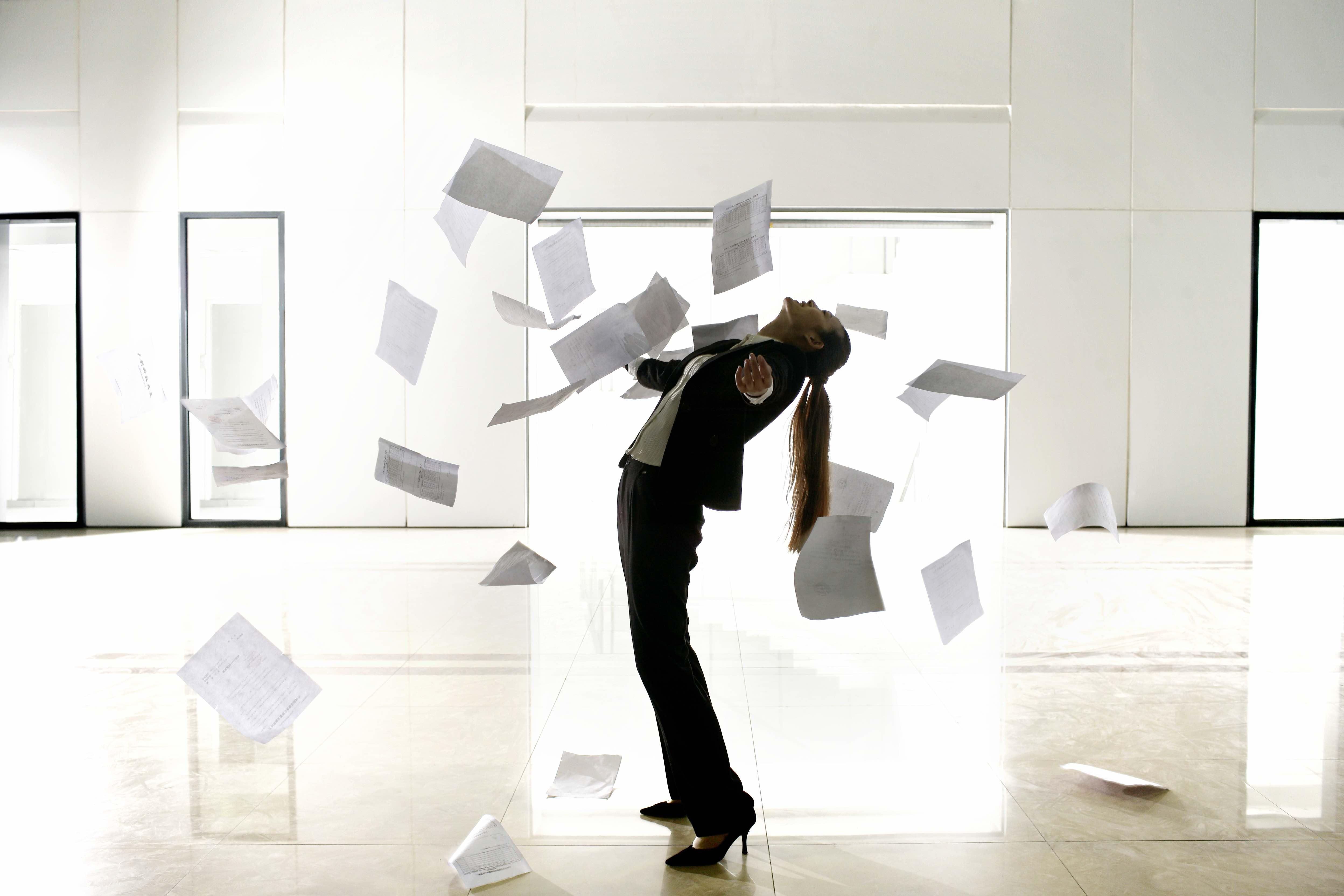 A business woman throws papers in the air.