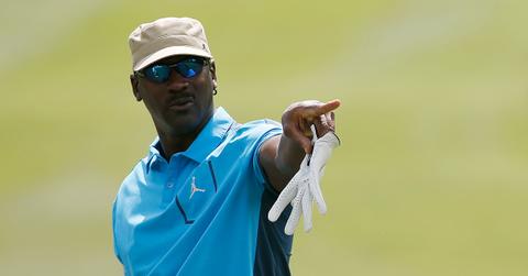 Michael Jordan pointing in a hat and sunglasses on a golf course.