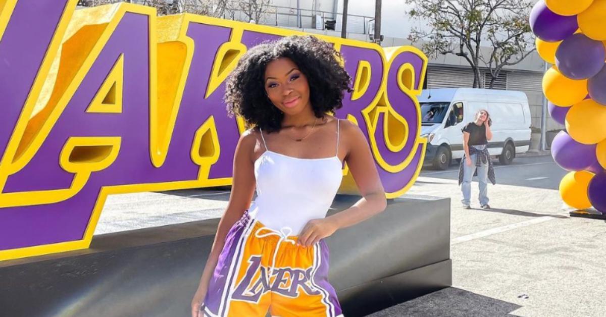 Quori-Tyler "QT" Bullock wears a white tank top and Lakers shorts as she poses in front of the Crypto.com Arena.