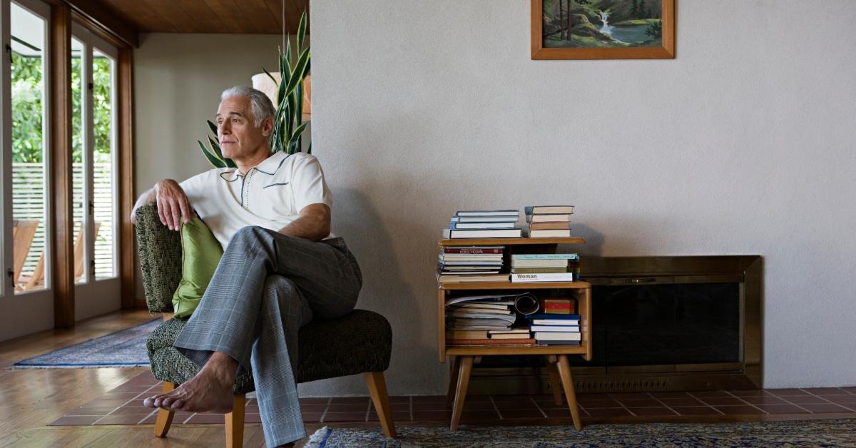 A senior man sitting on chair in living room, looking away