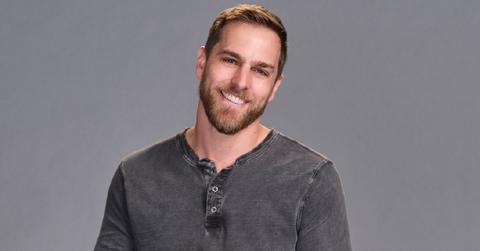 Adam smiles and poses in front of a grey background for his official portrait for 'Claim to Fame' Season 3.