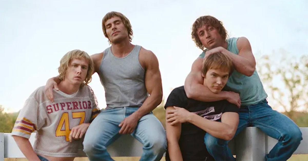 The cast of 'The Iron Claw' pose together sitting on a fence post. 