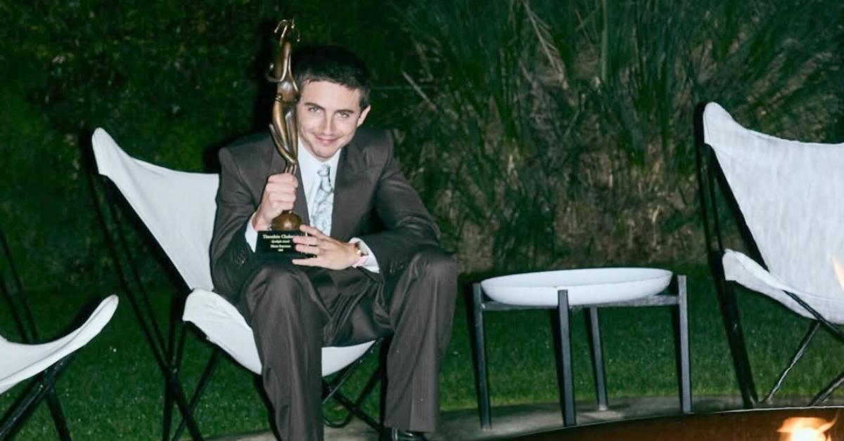 Timothée Chalamet sits in front of a fire with one of his awards.