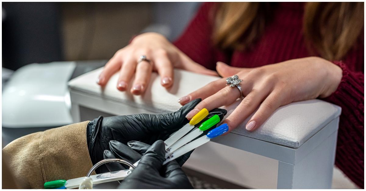A nail salon employee giving a woman options for her nail color