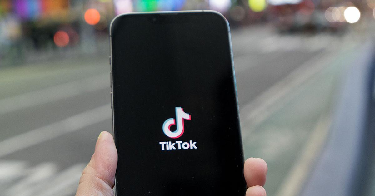 The TikTok logo on a phone being held in a hand. 