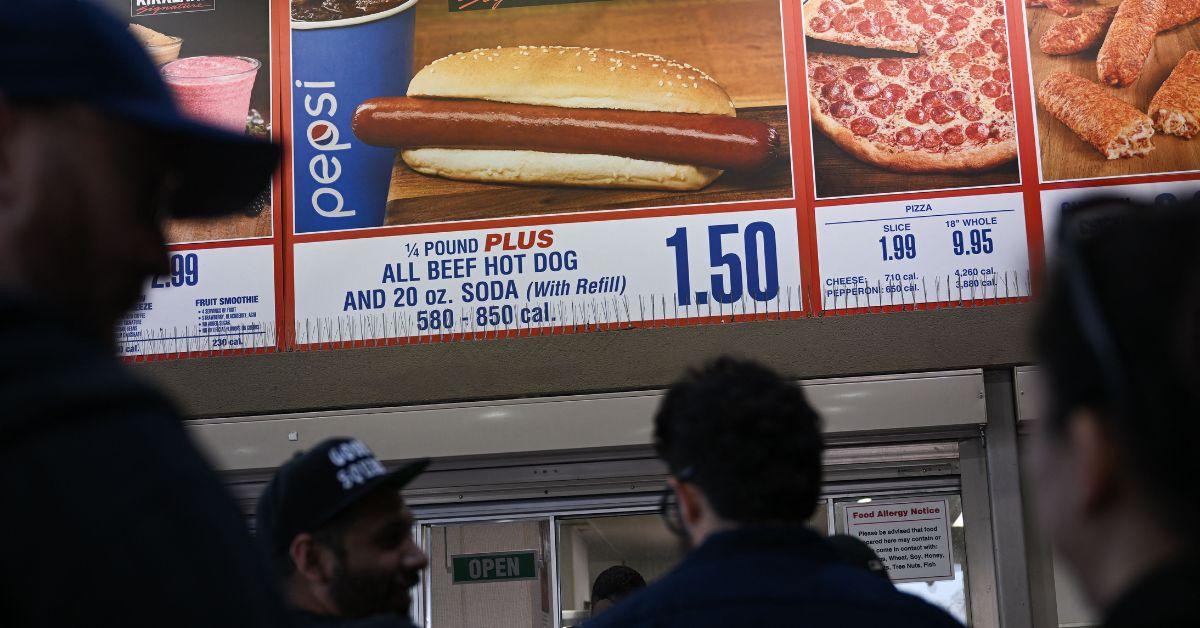 Customers wait in line to order below signage for the Costco Kirkland Signature $1.50 hot dog and soda combo