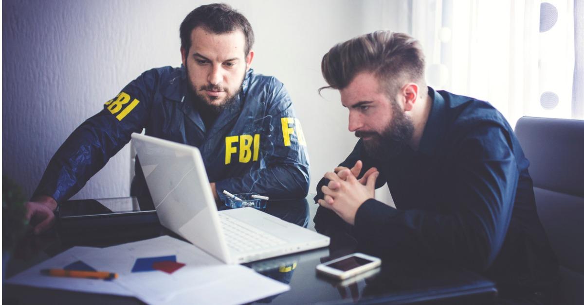 two agents looking at laptop picture id