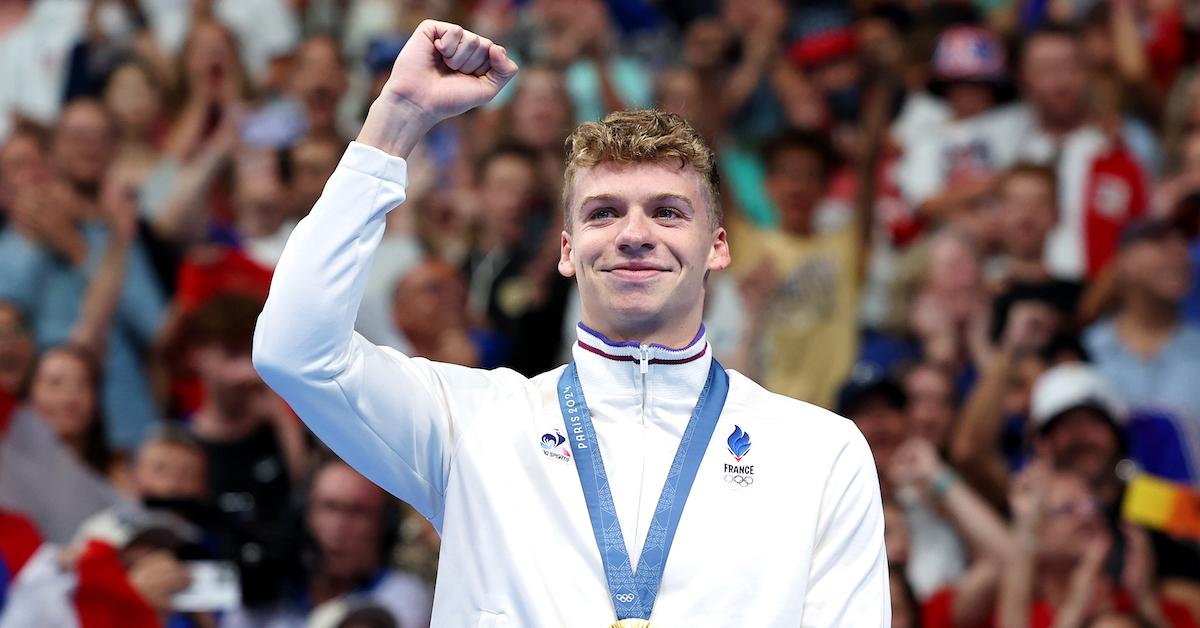 Leon Marchand of Team France celebrates on the podium during the Swimming medal ceremony after the Men’s 400m Individual Medley Final on day two of the Olympic Games Paris 2024 at Paris La Defense Arena on July 28, 2024 in Nanterre, France