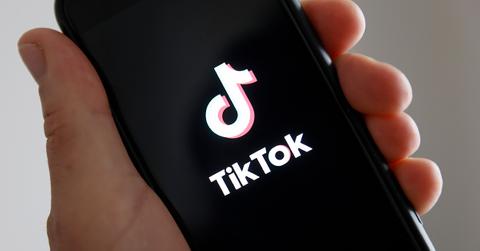 A TikTok logo on a phone in a person's hand.