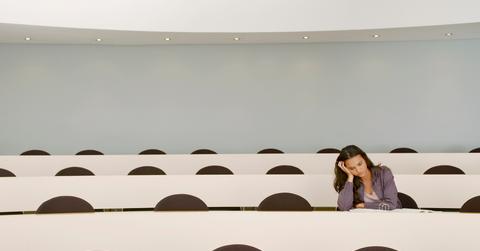 A photo of a student, stressed, taking an exam in an empty lecture room.