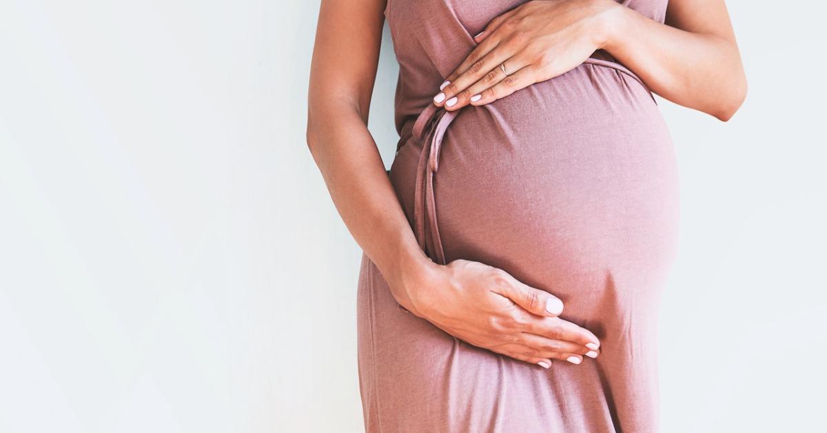 pregnant woman in dress holds hands on belly on a white background picture id