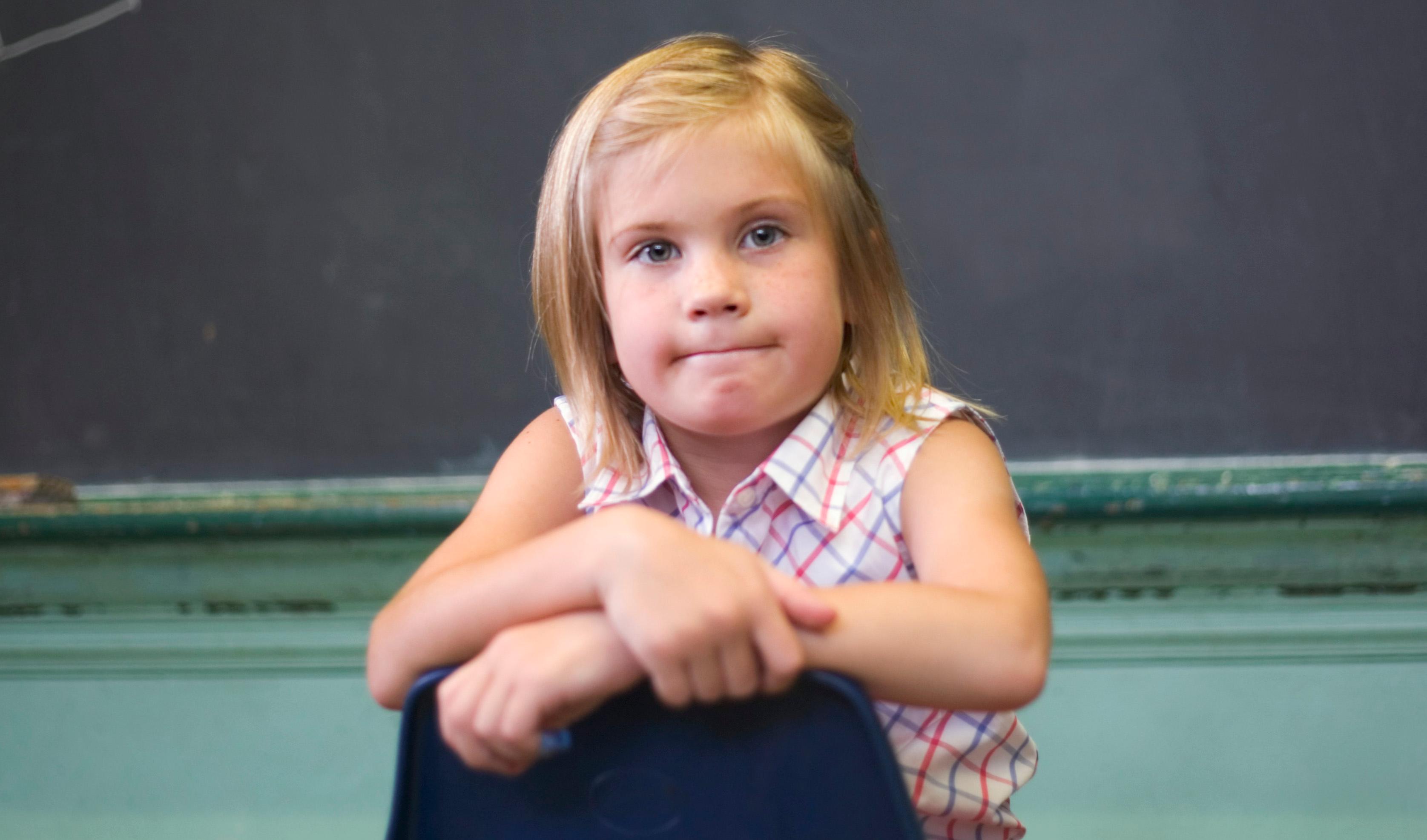 djevojka sjedi natraške na školskom stolcu