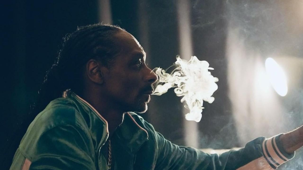 Snoop Dogg wearing a green jacket and smoking weed