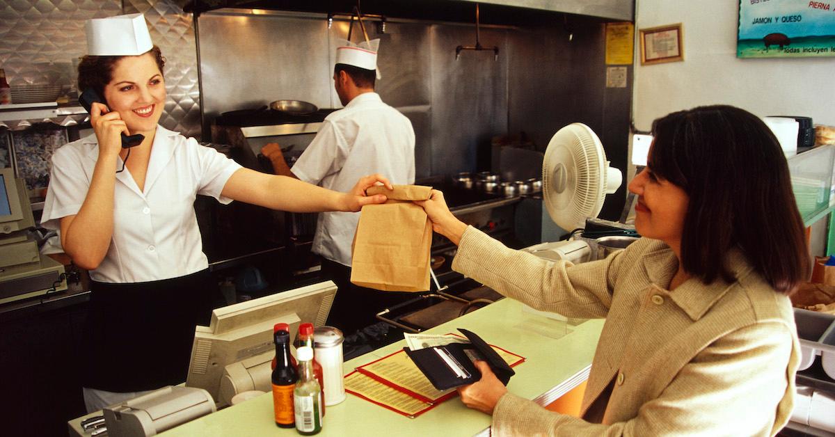 A restaurant worker handing a bag to a customer