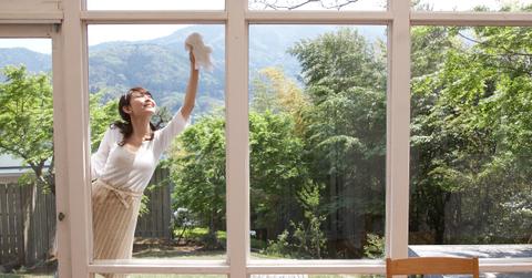 A woman cleans windows at a home