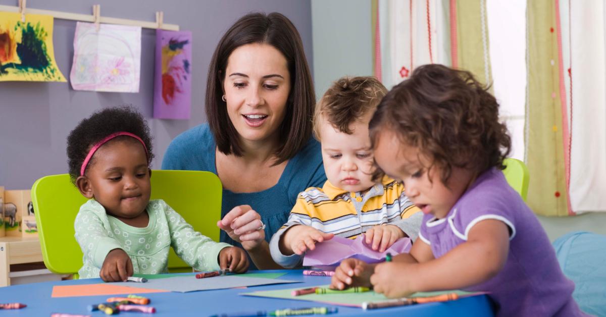 A teacher and three toddlers in daycare.