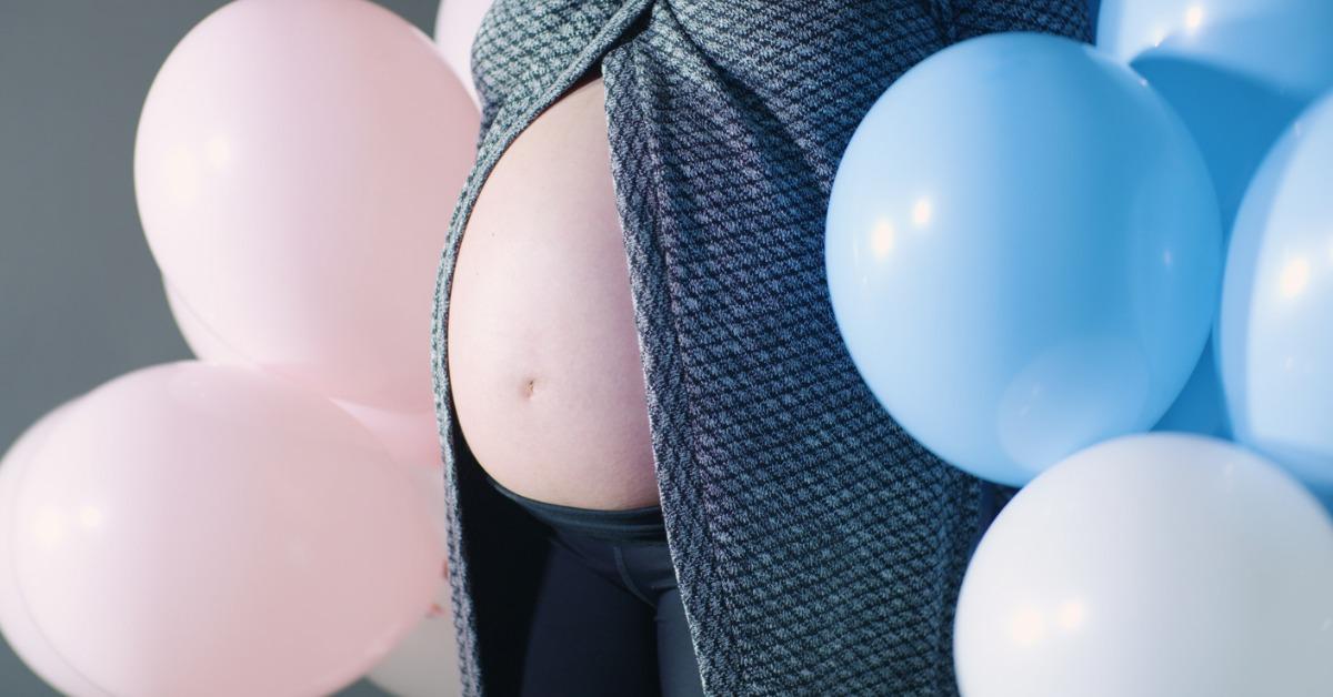 close up pregnant belly baby bump girl boy pink blue colored balloons picture id