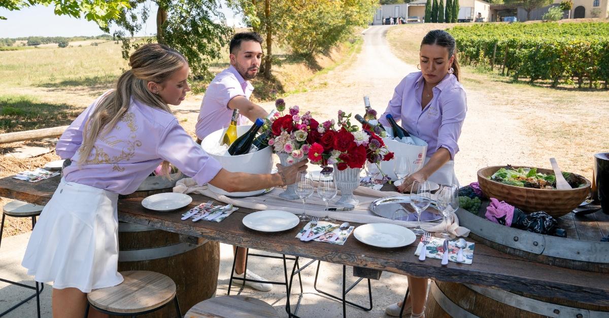 Hannah Fouch, Stephen Alsvig, and Priscila Ferrari set a table during Season 1 of 'Vanderpump Villa.'