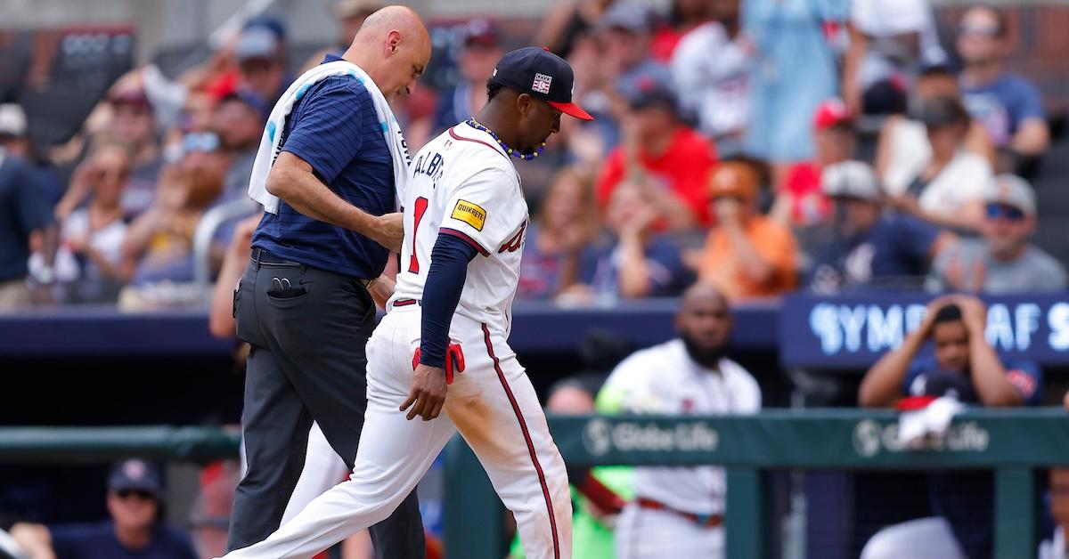 Ozzie Albies walks off field with trainer George Poulis after wrist injury in Braves game against Cardinals