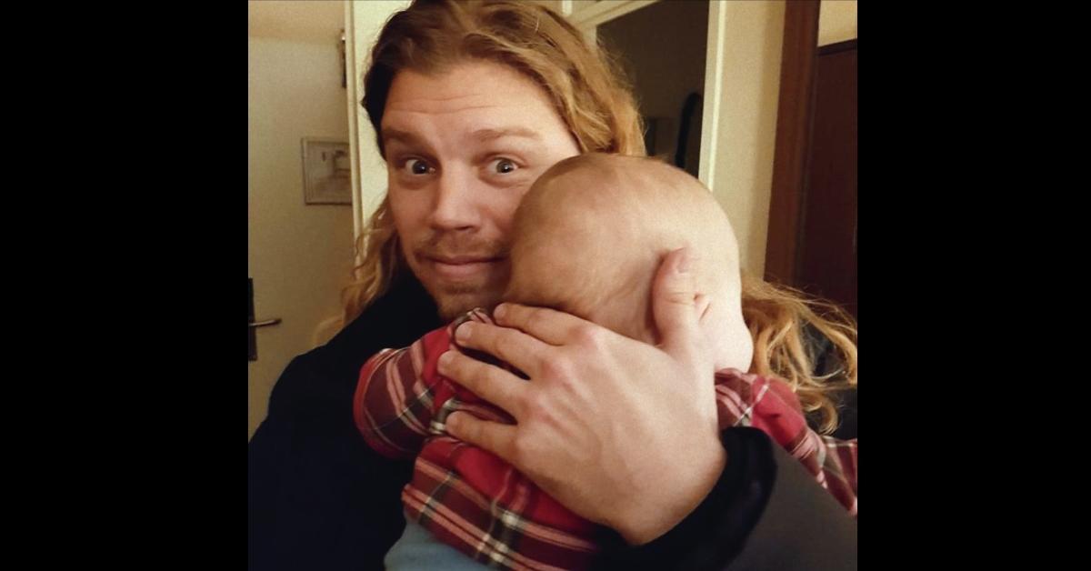 Jonathan Meijer smiles while holding a baby