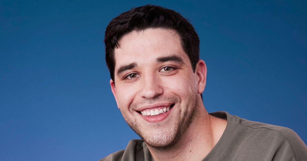 Devin Strader smiles against a blue backdrop