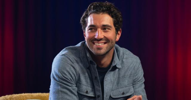 'The Bachelor' Season 28 lead Joey Graziadei sits and sports a grin while dressed in a cozy gray flannel utility shirt