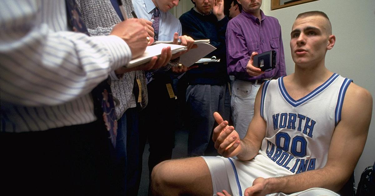 Eric Montross speaking to reporters in a North Carolina uniform. 