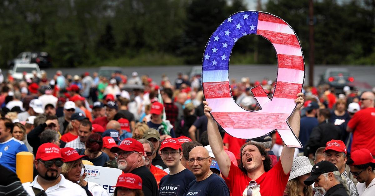 Man holding Q sign