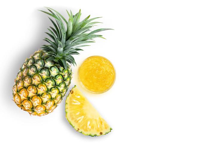 A whole pineapple and a slice of a pineapple