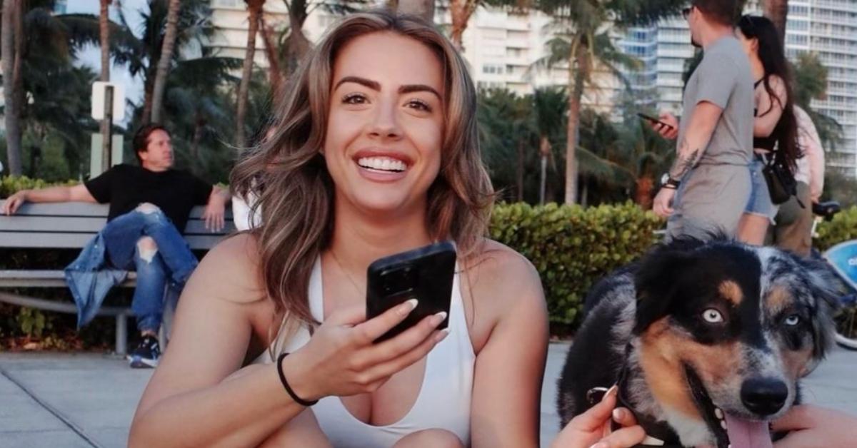 Dee Valladares sitting on Miami Beach with her dog.