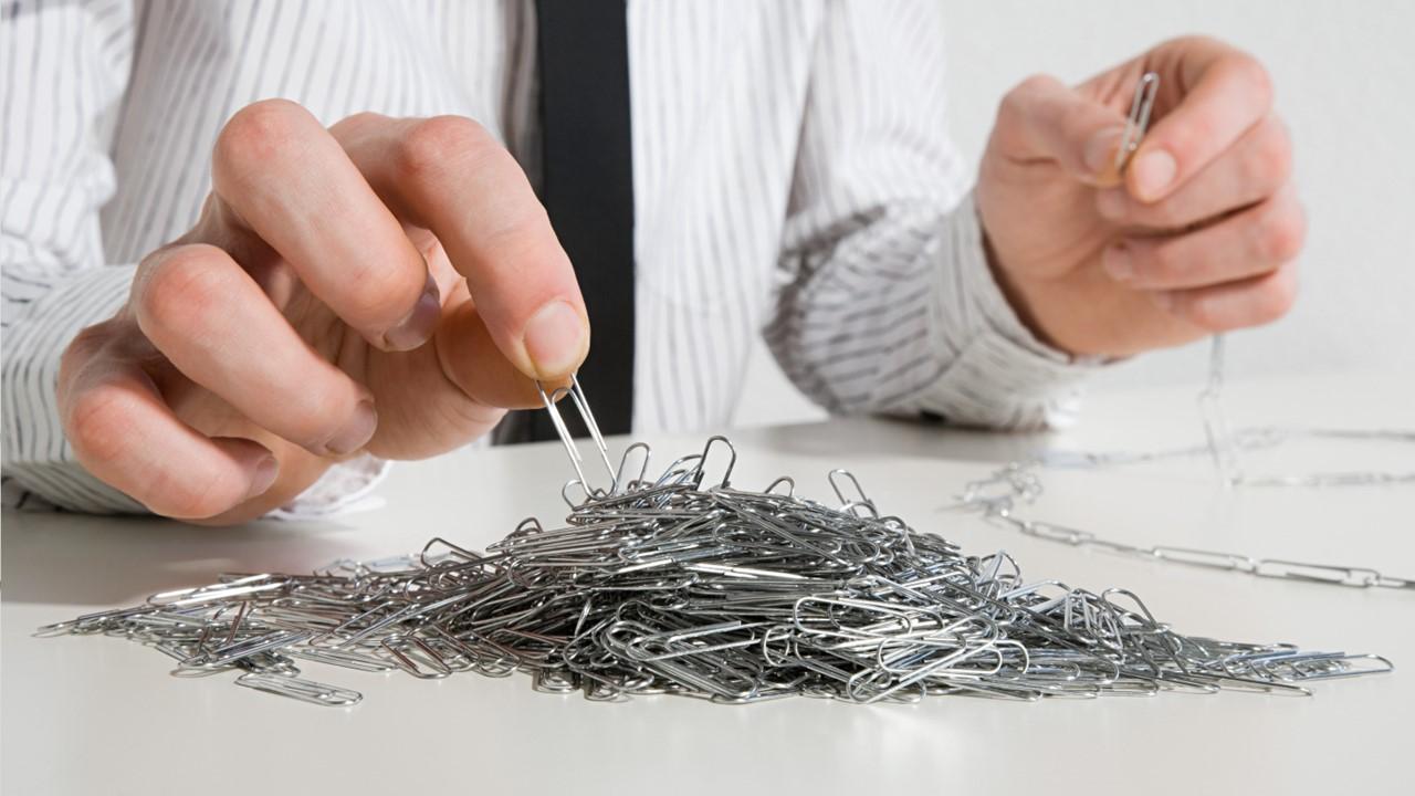 A man using a pile of paper clips to make a chain