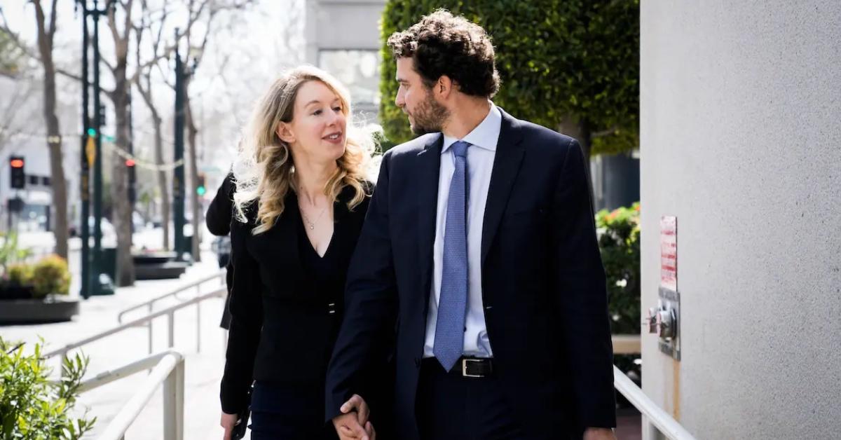 Elizabeth Holmes and Billy Evans walking down the sidewalk holding hands.