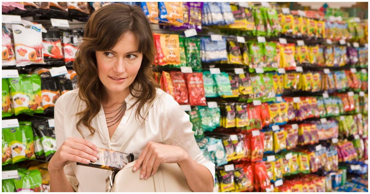 A woman stealing a candy bar at a grocery store