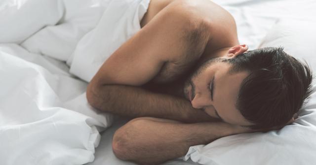 Man sleeps nude in bed.