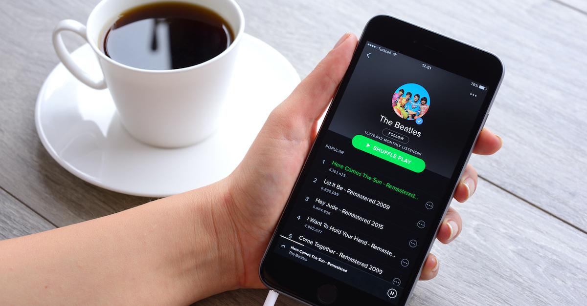 Spotify app on phone next to cup of coffee