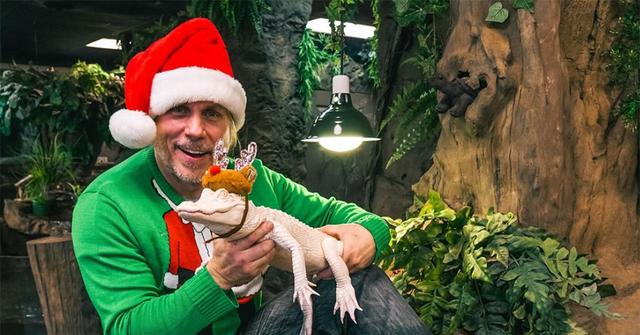 Brian Barczyk sitting with a lizard and a santa hat.