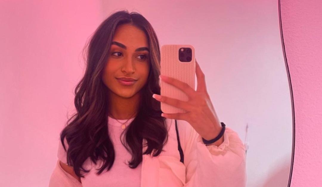 morgan bailey taking mirror selfie with phone against a pink background