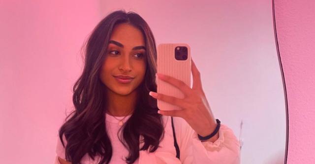 morgan bailey taking mirror selfie with phone against a pink background