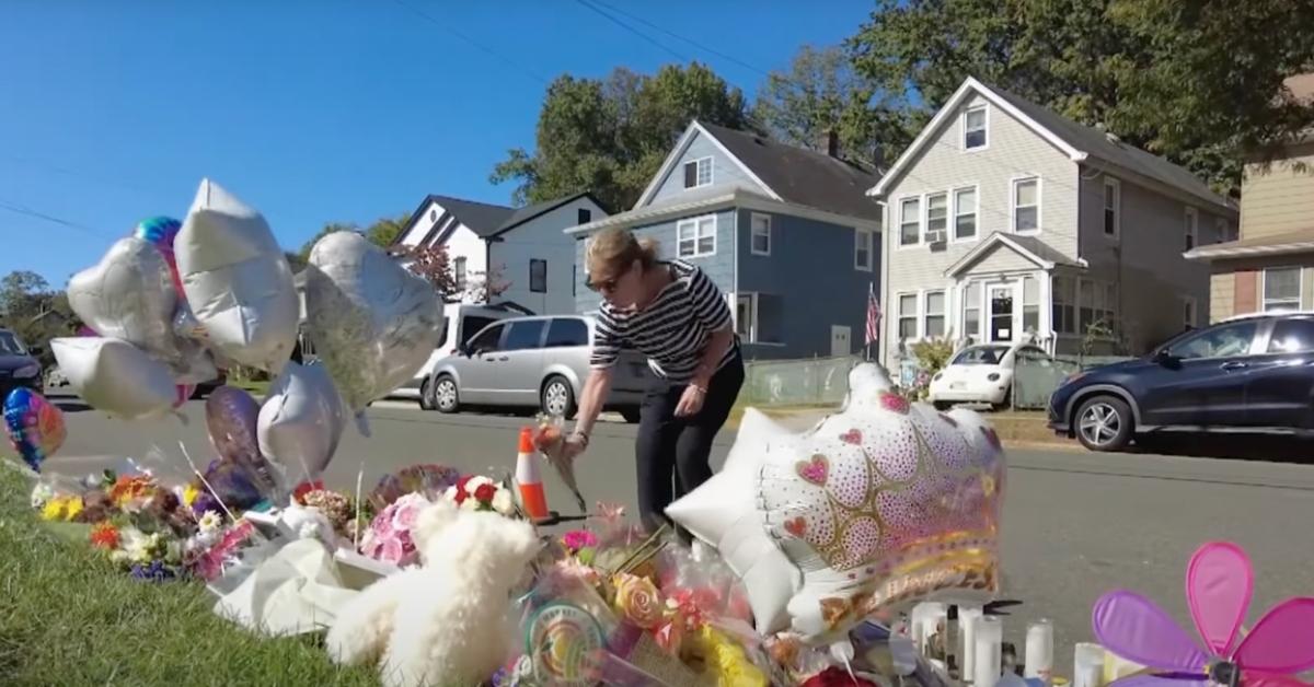 A woman places flowers next to a vigil for Maria Niotis and Isabella Rose Salas