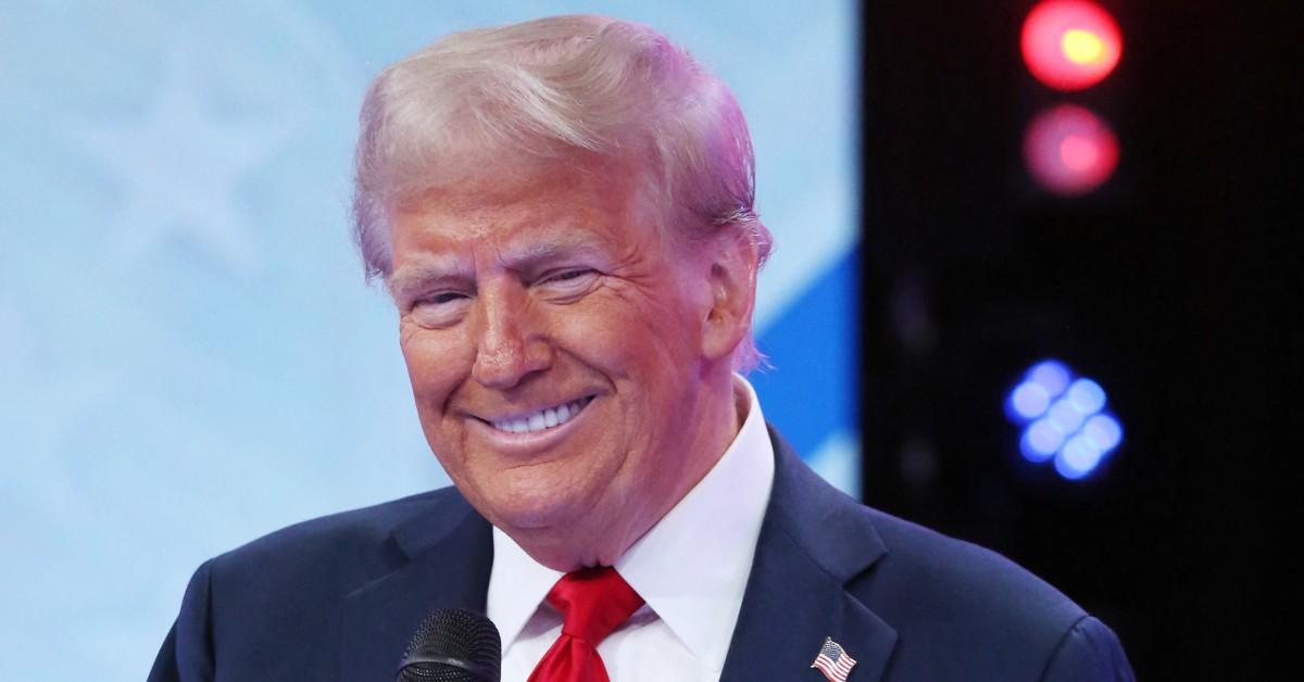 President Donald Trump smiling and holding a microphone