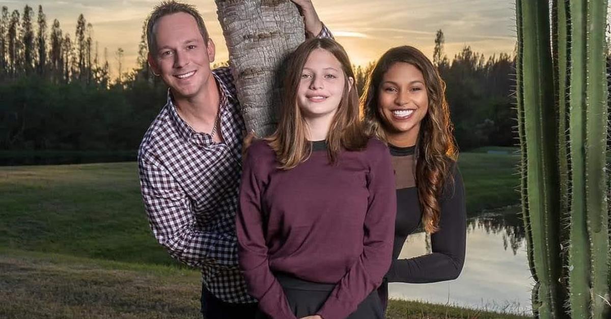 Brian and Mika Kleinschmidt post with their daughter Jade by a tree