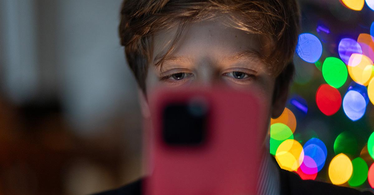 A kid looking at a phone with the phone unfocused. 