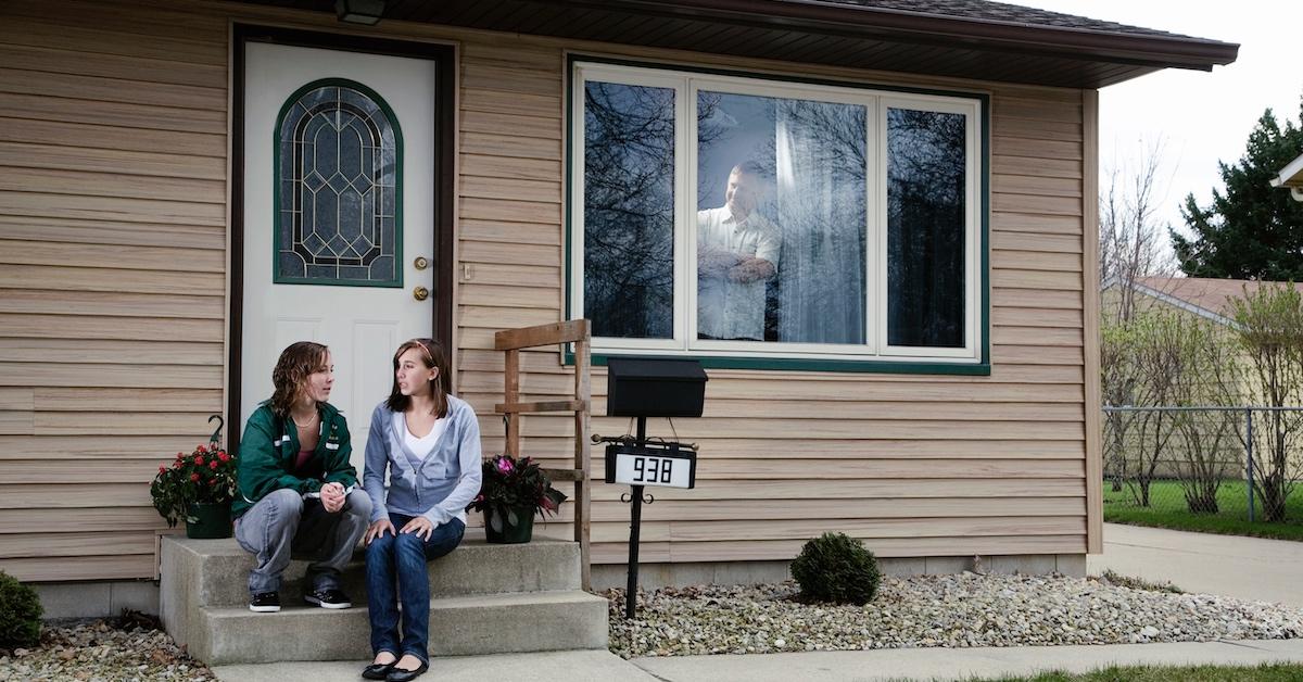 Teenagers talking outside with a parent watching