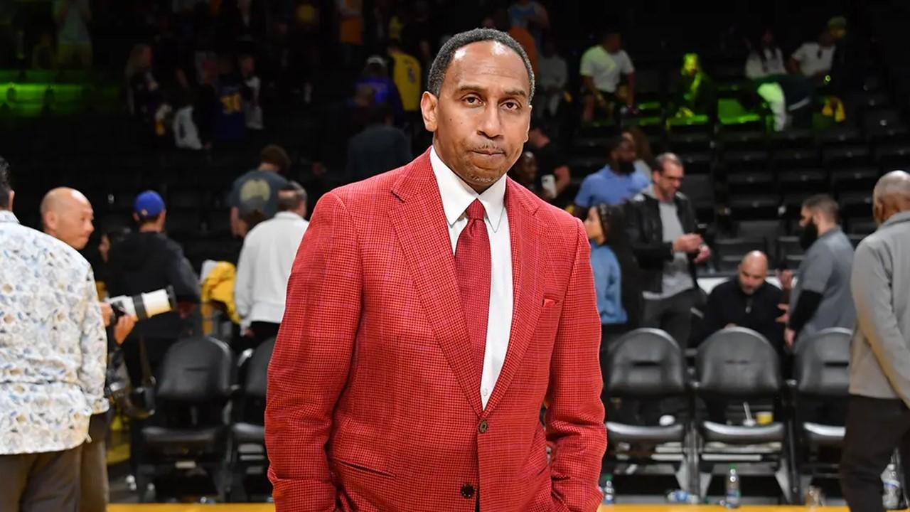 Stephen A. Smith wearing a red suit at a Los Angeles Lakers game. 