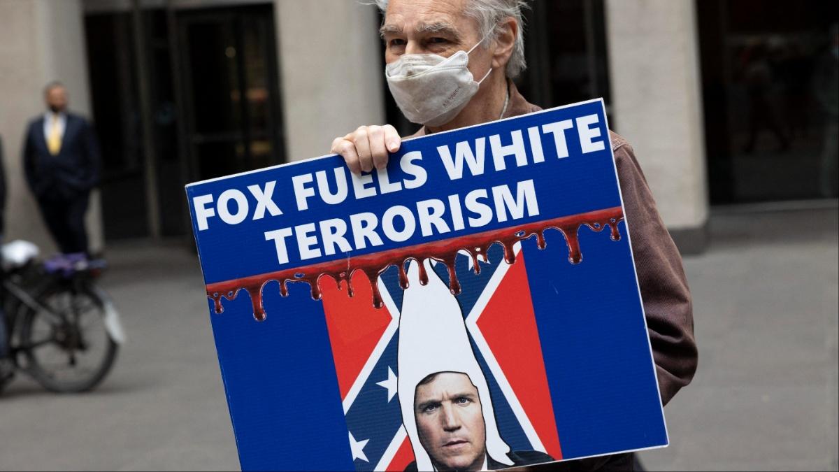 A man protests Fox News and Tucker Carlson.