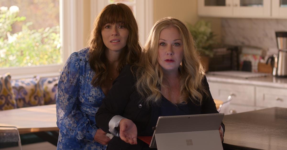 Linda Cardellini as Judy Hale and Christina Applegate  as Jen Harding looking afraid while on a tablet in the kitchen on 'Dead to Me'.