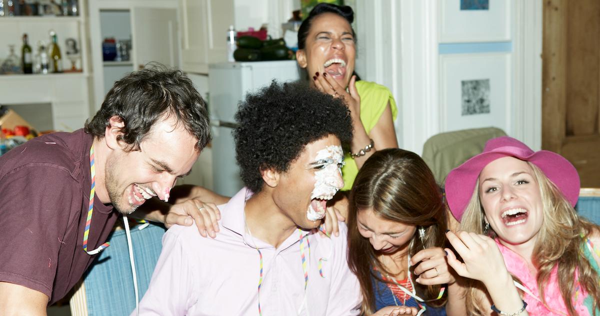 people laughing at a party after someone's face was shoved in pie