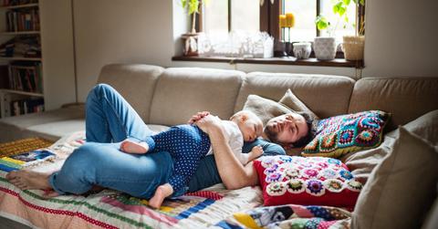 Man with a baby girl sleeping on the sofa.
